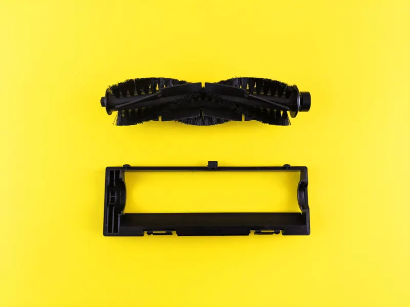 Close-up of vacuum cleaner components on vibrant yellow surface, highlighting maintenance and cleaning