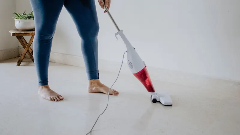 Close-up of a woman vacuuming a clean marble floor barefoot, showcasing home cleaning and maintenance
