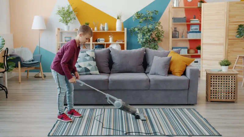 Young boy vacuuming carpet in colorful, modern living room setting